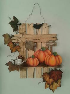 a wooden pallet with pumpkins, leaves and a bird on it's back