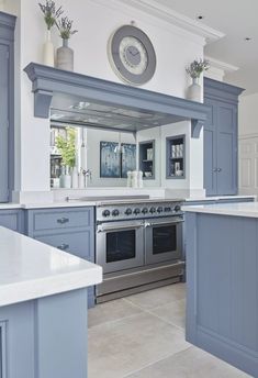 a kitchen with blue cabinets and an oven in the center is decorated with white marble countertops