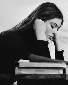 a black and white photo of a woman sitting at a desk with her hand on her head