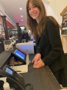 a woman standing behind a counter with laptops on it