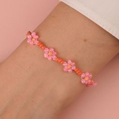 a woman's arm with pink and orange flowers on it, wearing a bracelet