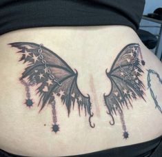 a woman's back with two wings and stars on it, hanging from chains