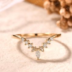 a yellow gold ring with three diamonds on the side, and a pine cone in the background