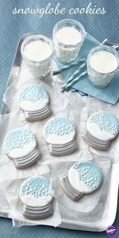 some cookies are sitting on a tray with frosting and spoons next to them