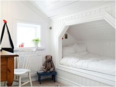 there is a stuffed animal sitting in the corner of this room with white walls and wood flooring