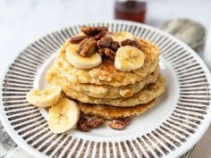 a stack of pancakes topped with bananas and pecans