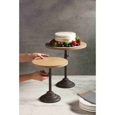 two tiered cake stands with fruit on top, one holding a plate and the other holding