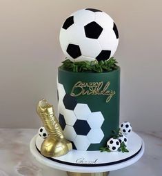 there is a soccer cake on top of a plate with gold shoes and a ball