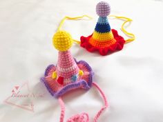 two crocheted hats sitting on top of a white bed next to each other