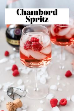 two glasses filled with raspberry spritz next to bottles of champagne and ice