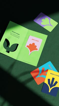 four different colored cards sitting next to each other on a green surface with shadows coming from them