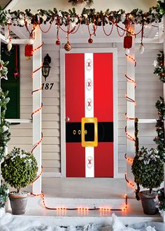 a red and white door decorated with christmas lights, garlands and decorations on the front porch