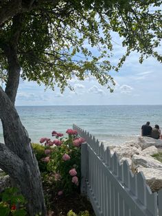 two people sitting on a bench near the ocean