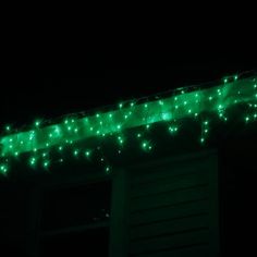 green lights are hanging from the roof of a house