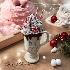 a hot cocoa drink with candy canes and marshmallows in it on a table