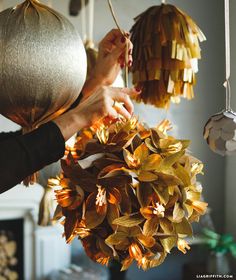 a woman is holding a bunch of paper flowers in front of her face and hanging them from the ceiling