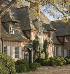 an old brick house with ivy growing on the roof and windows, surrounded by trees