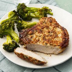 a white plate topped with meat and broccoli on top of a blue table cloth