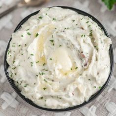 a black bowl filled with mashed potatoes on top of a white and gray tablecloth