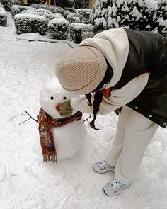 a person building a snowman outside in the snow