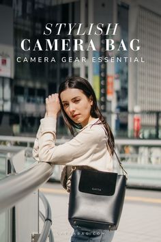 a woman is leaning against the railing with her camera bag