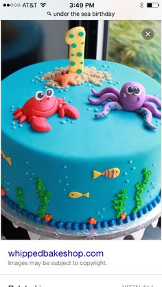 a blue cake with an octopus and crab on it's top is for a 1st birthday