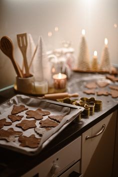 some cookies are sitting on a cookie sheet in the middle of a kitchen counter with candles and utensils