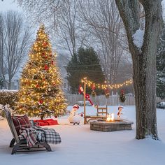 a decorated christmas tree in the middle of a snow covered yard with lights on it