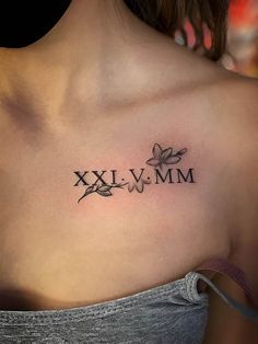 a woman's chest with the word xxvimm tattooed on her left shoulder