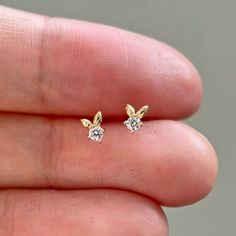 These delightful bunny-shaped earrings, accented with high quality CZ, are charming and versatile, perfect for both work and casual outfits. These earrings sold as a pair with gold push backs. ♡ Features  * Gold Kt: 14K solid gold * Available Gold Color: Yellow Gold * Number of Stones: 1 * Gemstone: Cubic zirconia * Stone Color: Flawless D Color * Stone Cut: Round Cut * Measurement: 3.3mm*4mm  * Stamped with 14K(Au585) hallmark  ♡ Shipping & Returns Orders placed Monday - Friday will ship within 3-7 business days. Please contact us if you need your order by a specific date. All orders over $300 require a signature upon delivery. Violet Gold Jewelry does not process or ship orders on Saturday, Sunday or on observed holidays. Applicable duties and taxes on all international orders will be co Tiny Gold Diamond Earrings For Gift, Small Rabbit, Tiny Bunny, Bunny Earrings, Dainty Studs, Gold Number, Gold Sparkle, Stone Cuts, Cz Diamond