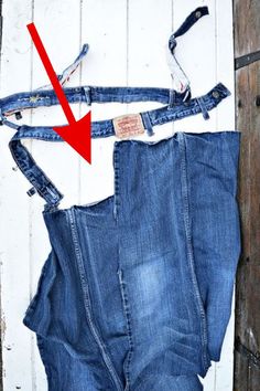 an old pair of jeans is being repaired with a red arrow pointing to the bottom