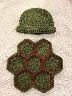 two crocheted hats sitting on top of a white bed next to each other