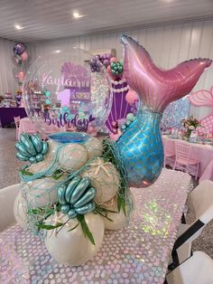 a table topped with balloons and mermaid decorations