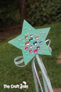 a green star shaped pinwheel with jewels on it's side and ribbon around the top