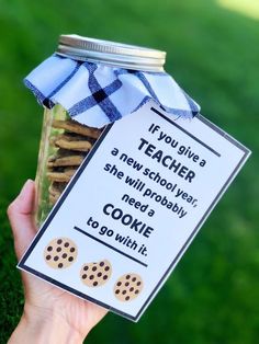 a person holding up a jar with cookies in it and a teacher's new school year card