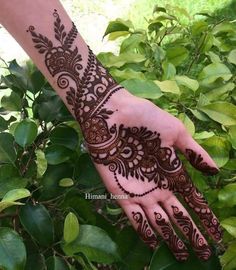 a hand with henna tattoos on it and some leaves in front of the palm