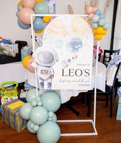 an astronaut themed party with balloons and streamers in the shape of stars, planets, and a sign that says leo's