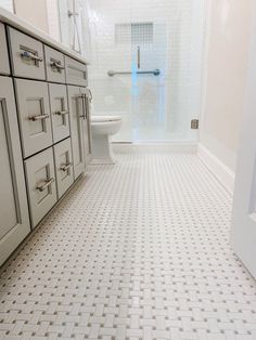 a bathroom with white cabinets and tile flooring next to a walk - in shower