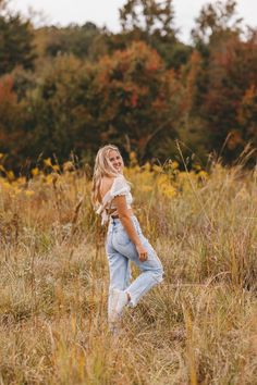 a woman standing in the middle of a field with her hands on her hips and looking off into the distance