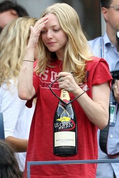 a woman in a red shirt holding a bottle of wine