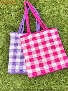 two crocheted bags sitting on top of a green grass covered field next to each other