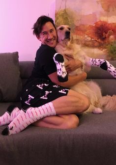 a woman sitting on top of a couch holding a dog