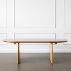 a wooden table sitting in front of a white wall with wood trim on the edge