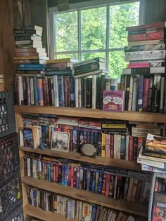 a bookshelf filled with lots of books in front of a window next to a book shelf