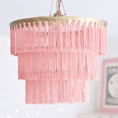 a pink chandelier hanging from the ceiling in a room with white walls and lights