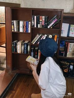 a woman sitting in front of a book shelf filled with books