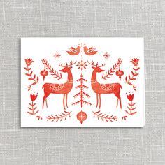 a card with red deers and flowers on the front, sitting on a gray surface