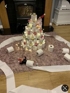 a christmas tree made out of rolls of toilet paper on the floor in front of a fire place