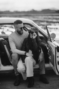 a man and woman sitting on the back of a car