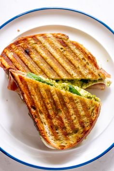 a grilled sandwich on a white plate with blue trim